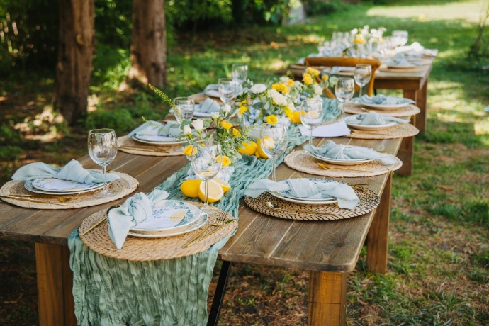 Outdoor dining table set for a party with floral decorations.